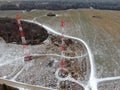 Aerial view telecommunication towers of mobile communication on the background of green field is covered with white snow. Royalty Free Stock Photo