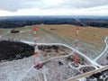 Aerial view telecommunication towers of mobile communication on the background of green field is covered with white snow. Royalty Free Stock Photo