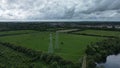 Aerial view of tension power lines and pylon meadowland with suburbs in the background, UK