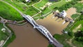 Aerial view of Tha Chomphu White Bridge, Lamphun, Thailand with river, forest trees and green mountain hill. An old railway bridge