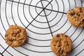 Aerial view of three chocolate cookies on round black rack, on white marble table, selective focus Royalty Free Stock Photo