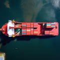 Aerial view to cargo ship with colorful containers on the open sea, transportation concept