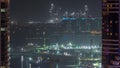 Aerial view to Dubai marina skyscrapers with construction site and Palm Jumeirah Island on background night timelapse. Royalty Free Stock Photo