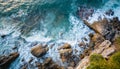 Aerial view top seashore, rocky coast, waves crashing on rock cliff. Blue ocean surface sunny summer Royalty Free Stock Photo