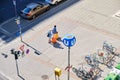 Aerial view of tourist couple with heavy yellow carry-on bags, walking on a wide sidewalk, near a subway station.