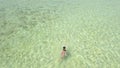 Aerial view of a tourist swimming in a crsytal clear ocean in the Philipines.