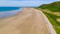 Aerial view of tourists on a huge, wide sandy beach on the coast of Wales Rhossili, Wales