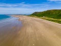 Aerial view of tourists on a huge, wide sandy beach on the coast of Wales Rhossili, Wales