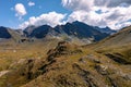 Aerial view toward a man at the tip of a rock formation admiring the vast and majestic alpine landscape, directed toward