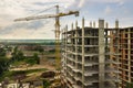 Aerial view of tower lifting crane and concrete frame of tall apartment residential building under construction in a city. Urban Royalty Free Stock Photo