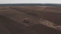 Aerial view tractor cuts furrows in farm field for sowing farm tractor with rotary harrow plow preparing land for sowing Royalty Free Stock Photo