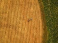 Aerial view of tractor making hay bale rolls in field