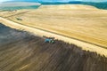 Aerial view of a tractor plowing black agriculture farm field after harvesting in late autumn