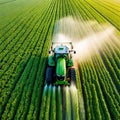 Aerial View of Tractor Spraying Pesticides on Green Soybean Plantation at Sunset Drone View