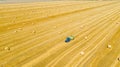 Aerial view of tractor tow trailed bale machine to collect straw from harvested field