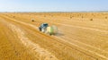 Aerial view of tractor tow trailed bale machine to collect straw from harvested field