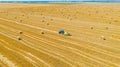 Aerial view of tractor tow trailed bale machine to collect straw from harvested field