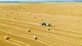 Aerial view of tractor tow trailed bale machine to collect straw from harvested field