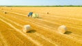 Aerial view of tractor tow trailed bale machine to collect straw from harvested field