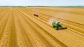 Above view on harvest season at agricultural plot, combine harvesting wheat, tractor drag trailers Royalty Free Stock Photo