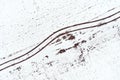 Aerial view of tractor tyre tracks in snowy field in winter morning