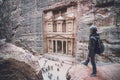 Aerial view of Treasury with a hiker, solo traveler, young man tourist on a cliff after reaching the top, Al Khazneh in the