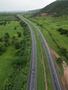 Aerial view of a tree-lined highway leading to a vast expanse of green grass in the distance Royalty Free Stock Photo