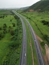 Aerial view of a tree-lined highway leading to a vast expanse of green grass in the distance Royalty Free Stock Photo