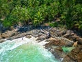 Aerial view of a tropical beach with rocky shoreline and lush green palm tree sat the shore Royalty Free Stock Photo