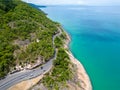 Aerial view of tropical winding road following blue ocean and rainforrest