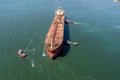 Aerial view of tug boat assisting big oil tanker. Large oil tanker ship enters the port escorted by tugboats Royalty Free Stock Photo