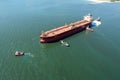 Aerial view of tug boat assisting big oil tanker. Large oil tanker ship enters the port escorted by tugboats Royalty Free Stock Photo