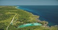 Aerial view of turquoise salt water lake at green tropic trees. Buildings, road at greenery valley Royalty Free Stock Photo