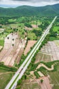 Aerial view of two-lane road through paddy fields and mountain range in rainy Royalty Free Stock Photo