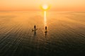 Aerial view of two people on stand up paddle boards on quiet sea at sunset. Warm summer beach vacation holiday Royalty Free Stock Photo