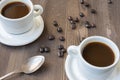 Aerial view of two white cups with coffee and spoon, on wooden table with coffee beans, Royalty Free Stock Photo
