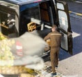 Aerial view of UPS driver in uniform next to his brown van loading unloading