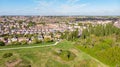 An aerial view of an urban area along a park under a majestic blue sky and white clouds