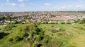 An aerial view of an urban area along a park under a majestic blue sky and white clouds