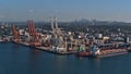 Aerial view of Vancouver container terminal with cranes and mooring bulk carriers and the skyscrapers of Burnaby.