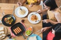 Aerial view of variety of food on the wooden table and friends eating dinner together