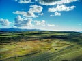 Aerial view of the vast green landscape at the Point of Ayre under a cloudy blue sky