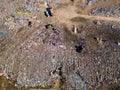 Aerial view of a vast landfill, where bulldozers are working and trucks are bringing new waste, huge flocks of birds are