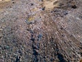 Aerial view of a vast landfill, where bulldozers are working and trucks are bringing new waste, huge flocks of birds are