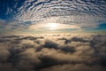 Aerial view of vibrant yellow sunrise over white dense clouds with blue sky overhead Royalty Free Stock Photo