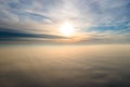 Aerial view of vibrant yellow sunrise over white dense clouds with blue sky overhead Royalty Free Stock Photo