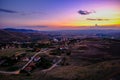 Aerial view of the village surrounded by the mountains gleaming under the sunset in the cloudy sky Royalty Free Stock Photo