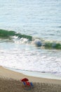 Aerial view of vivid color beach chairs and Parasol on the sandy beach with big waves