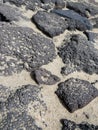 Aerial view of volcanic black rocks in the sand. Porous lava stones of different sizes in the sand. Geology background. Volcanic Royalty Free Stock Photo