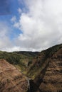 An aerial view of Waimea Canyon with two waterfalls, a moving helicopter blade and with large cumulus clouds in Kauai Royalty Free Stock Photo